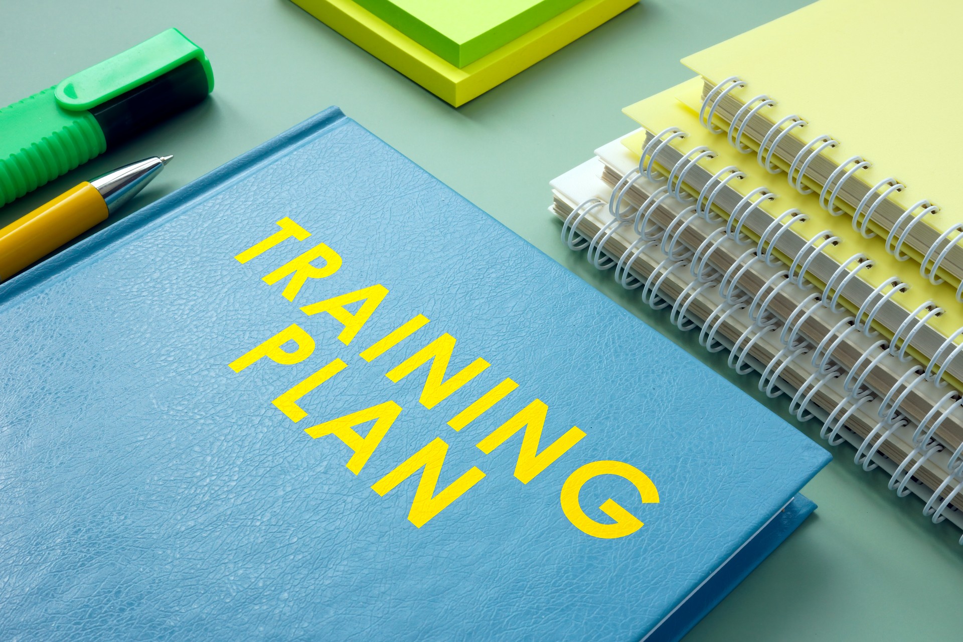 Training plan and stack of notebooks with pen.